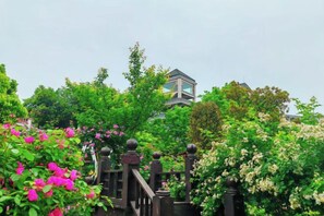 Ein Garten mit einem hölzernen Tor, üppigem Grün und einem Gebäude im Hintergrund.