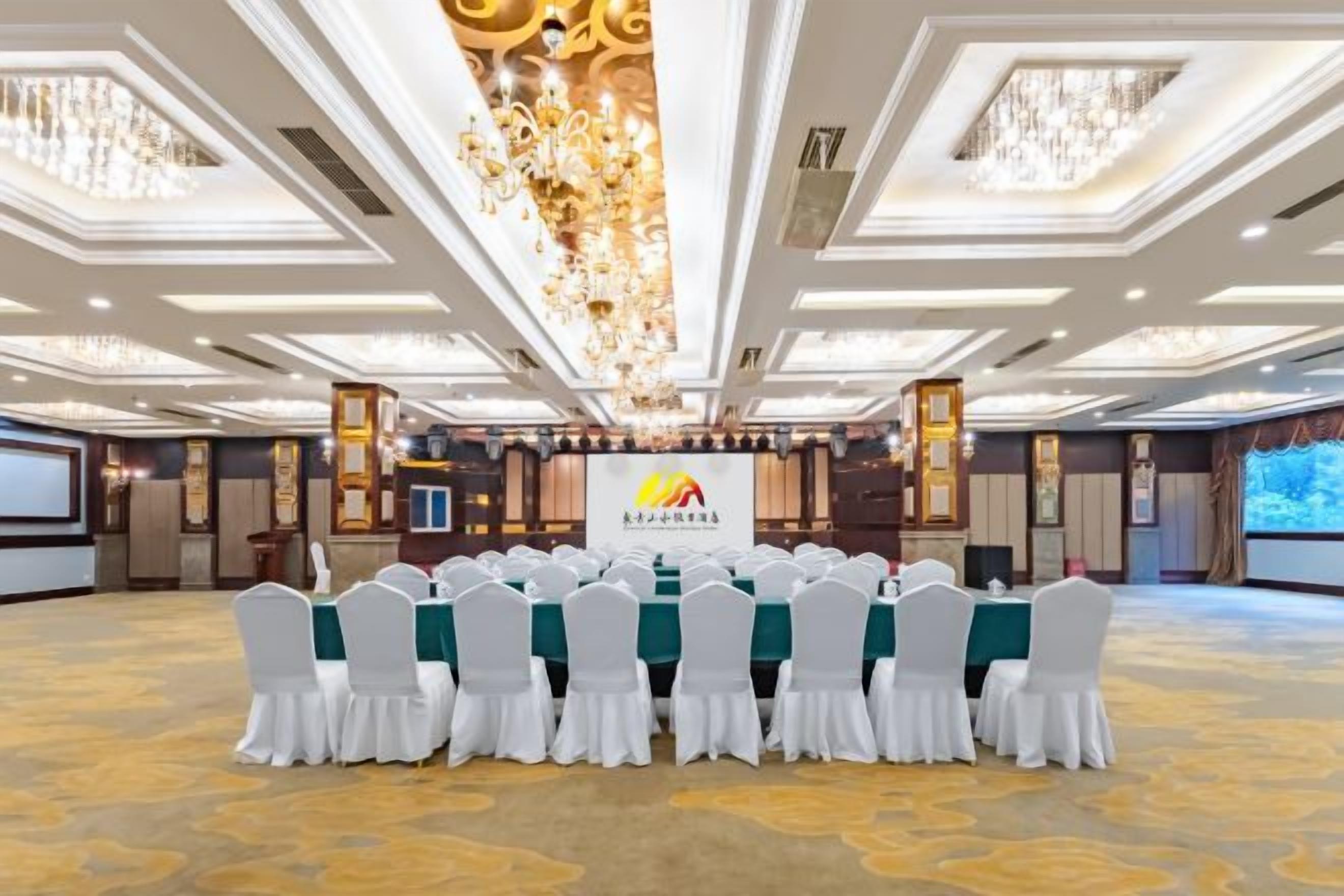 A conference room with a long table, white chairs, and a chandelier.