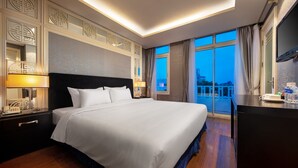 A hotel room with a large bed, bedside lamps, a desk with a telephone, and a view of the city at dusk. - Classy Boutique Hotel (Hanoi)