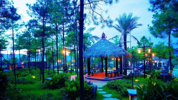 A thatched-roof gazebo surrounded by lush greenery and stone pathways. - Nanjing Baliyuanshu Vogue Hotspring Hotel (Nanjing)