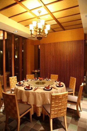 A dining area with a round table, chairs, and a chandelier.
