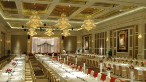 Een balzaal met lange tafels, kroonluchters en een podium.