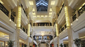 Een ruime lobby met een hoge plafond, een centrale trap en een glazen dakkoepel.