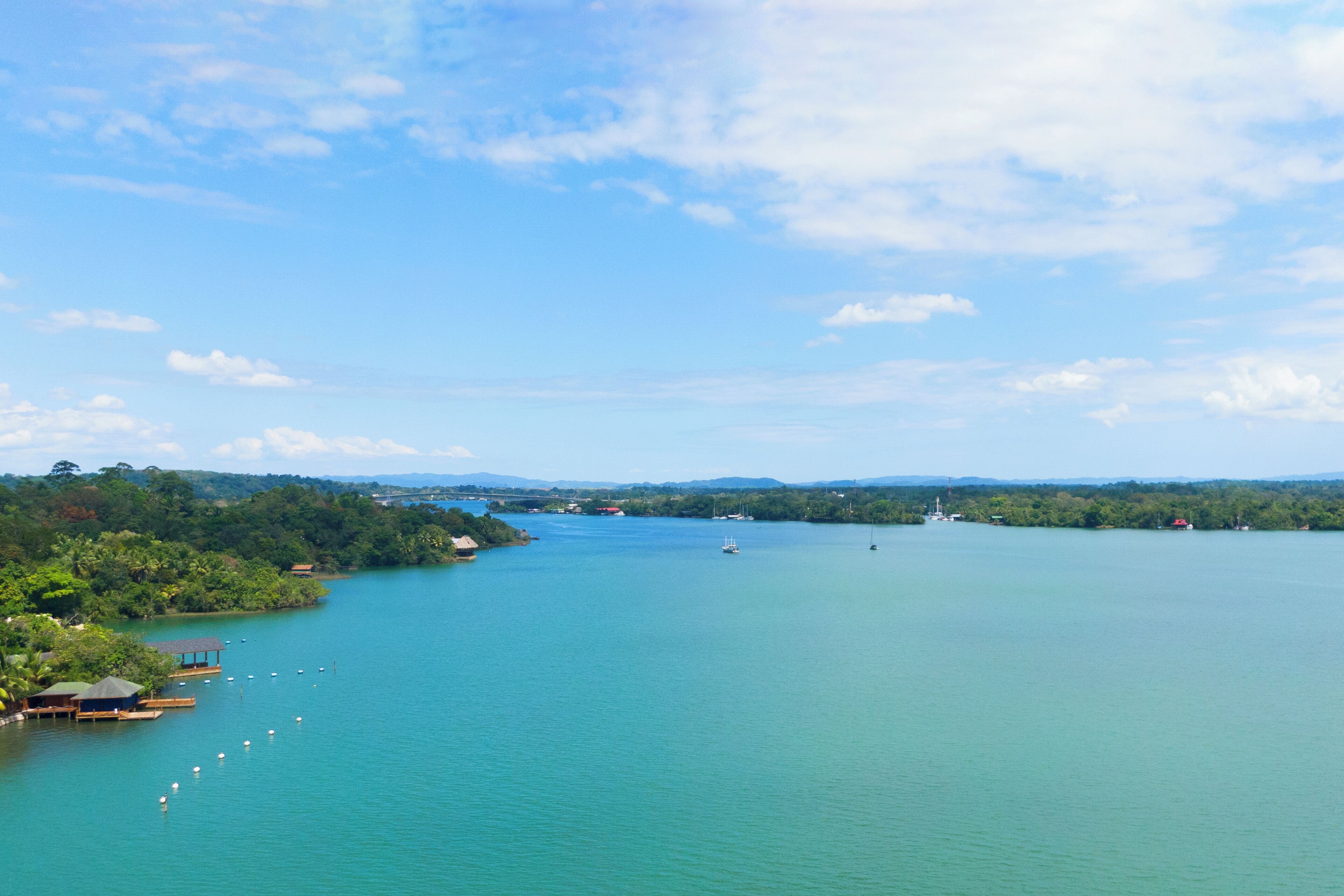 A calm lake with boats, a dock, and surrounding greenery.