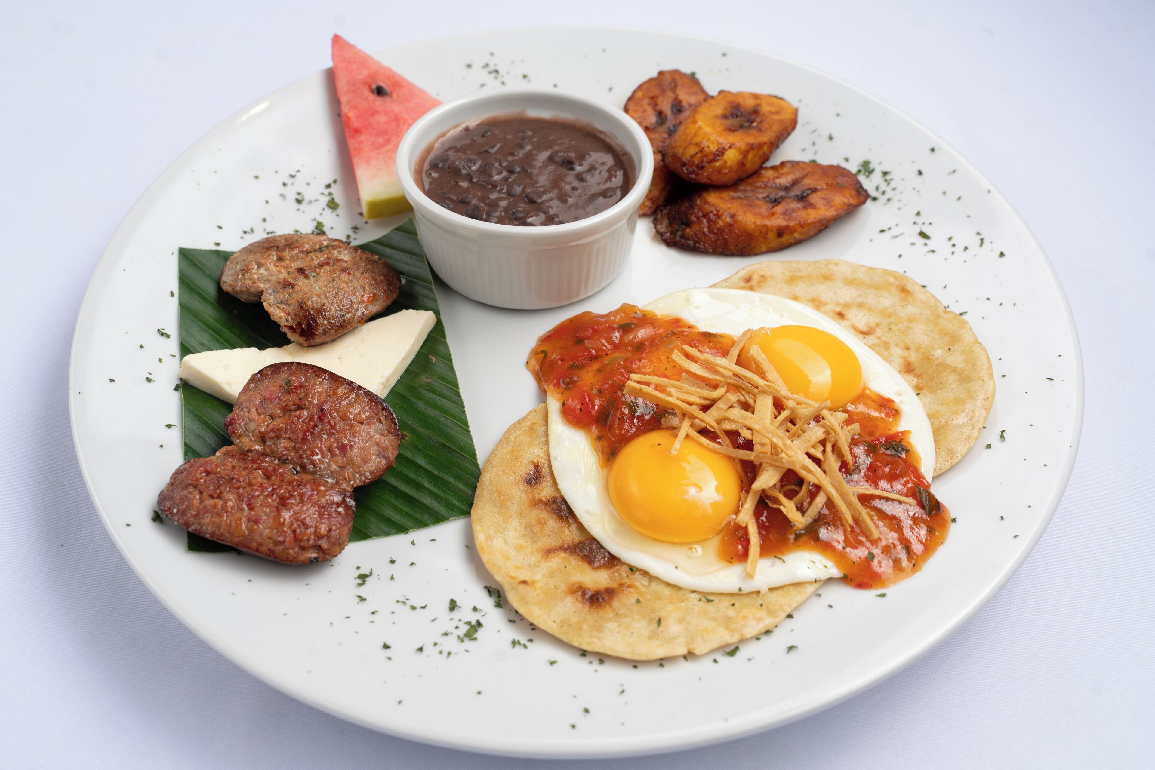 A plate with a variety of food items including eggs, meat, and plantains.