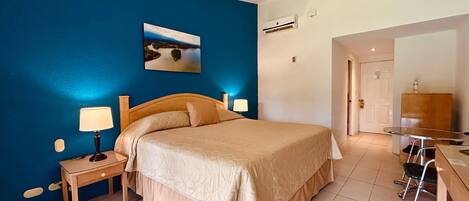 A bedroom with a bed, bedside tables, a desk, and a chair.