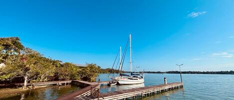A wooden dock extending into calm water with a sailboat moored at the end.
