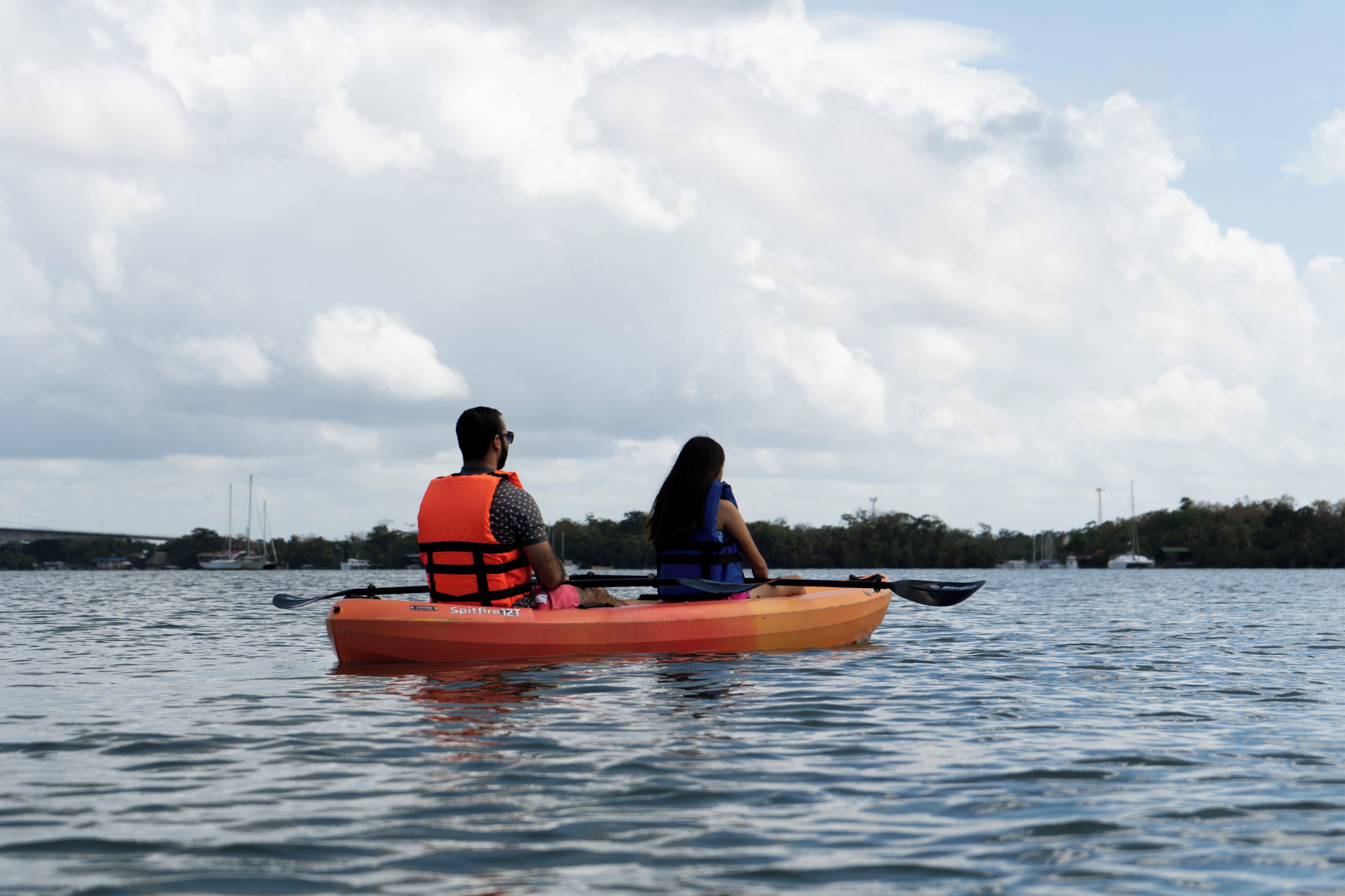Two people in a canoe on a body of water with a cloudy sky in the background.