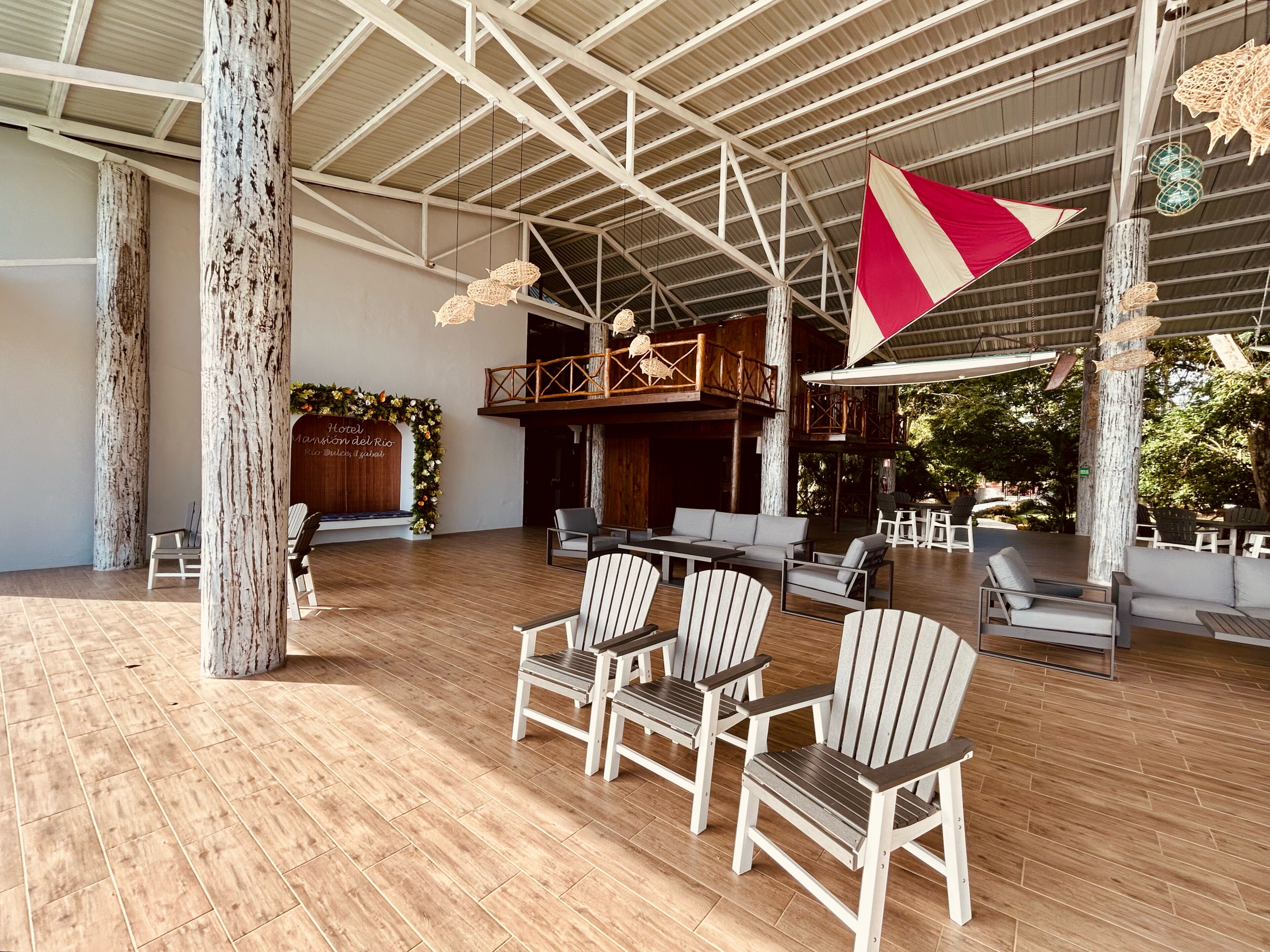 A spacious indoor area with wooden flooring, several chairs, a large flag, and a wooden structure with a balcony.