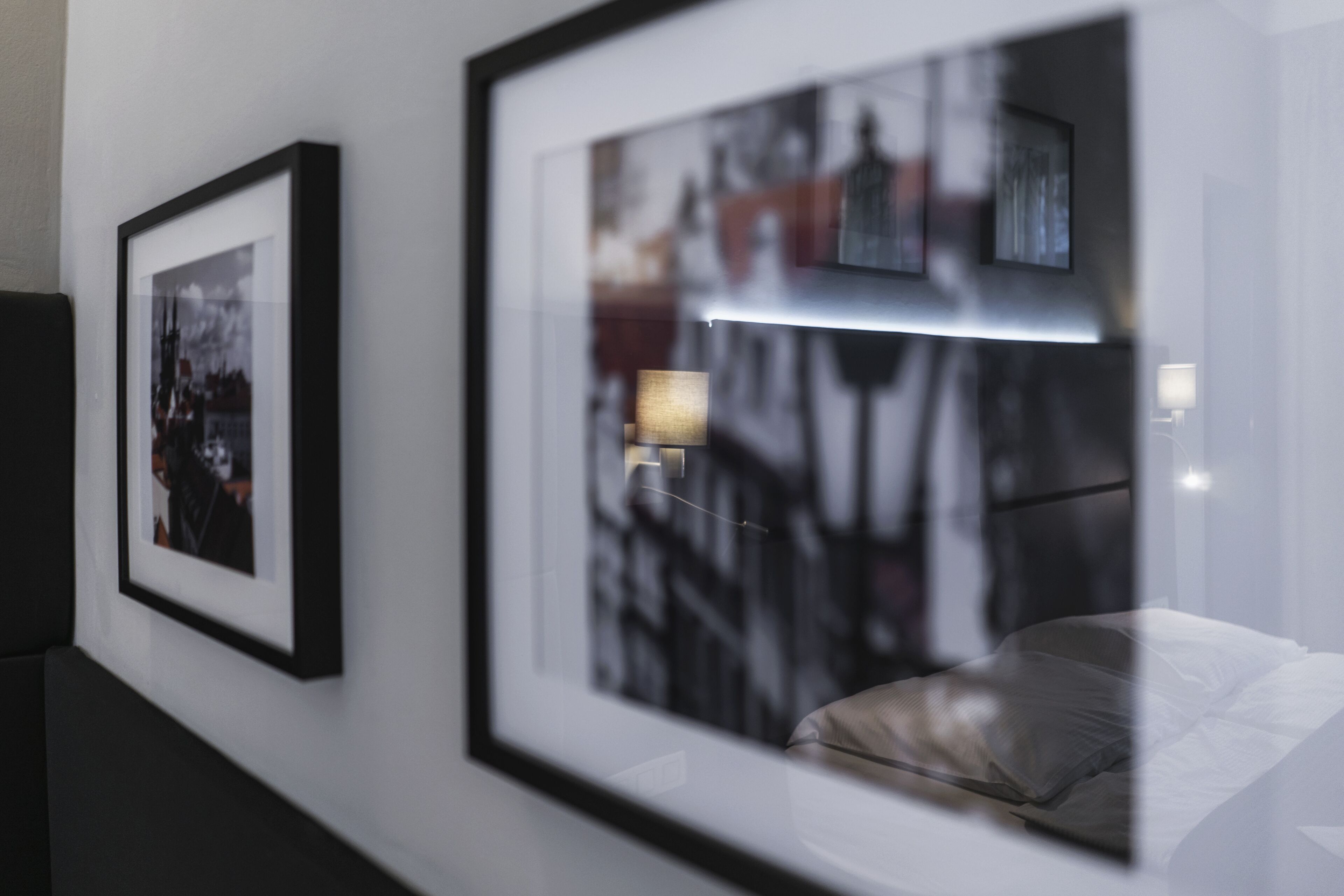 Ein Hotelzimmer mit einem Bett, einem Nachttisch und zwei gerahmten Fotos an der Wand.