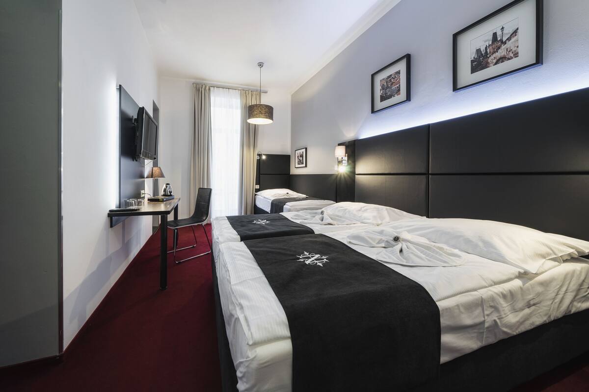 Habitación de hotel con una cama grande, un escritorio con silla, un televisor de pantalla plana y una ventana con cortinas.