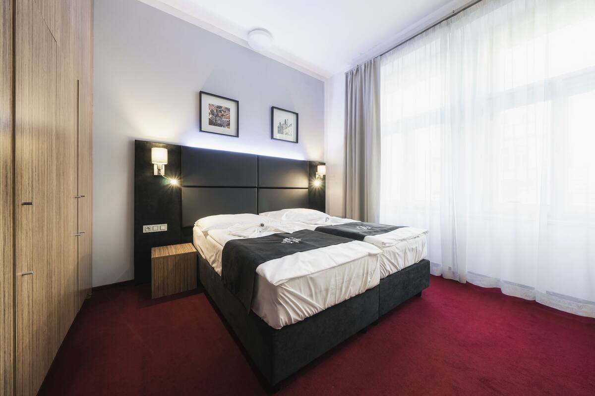 Una habitación de hotel con una cama grande, un armario de madera y una alfombra roja.
