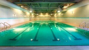 A large indoor swimming pool with multiple lanes, surrounded by walls with a tiled pattern and a greenish hue. - Ballard Inn (Seattle)