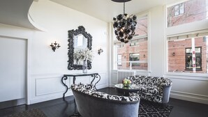 A modern lobby with a black and white patterned sofa, a black chandelier, and a large mirror on the wall. - Ballard Inn (Seattle)