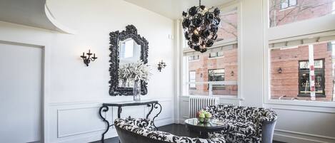 A modern lobby with a black and white patterned sofa, a black chandelier, and a large mirror on the wall.