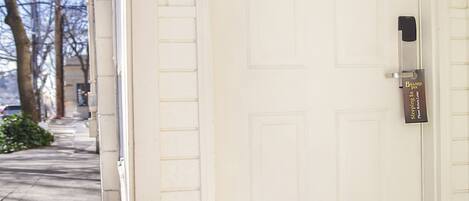 A white door with the number 107, a doorbell, and a doormat.