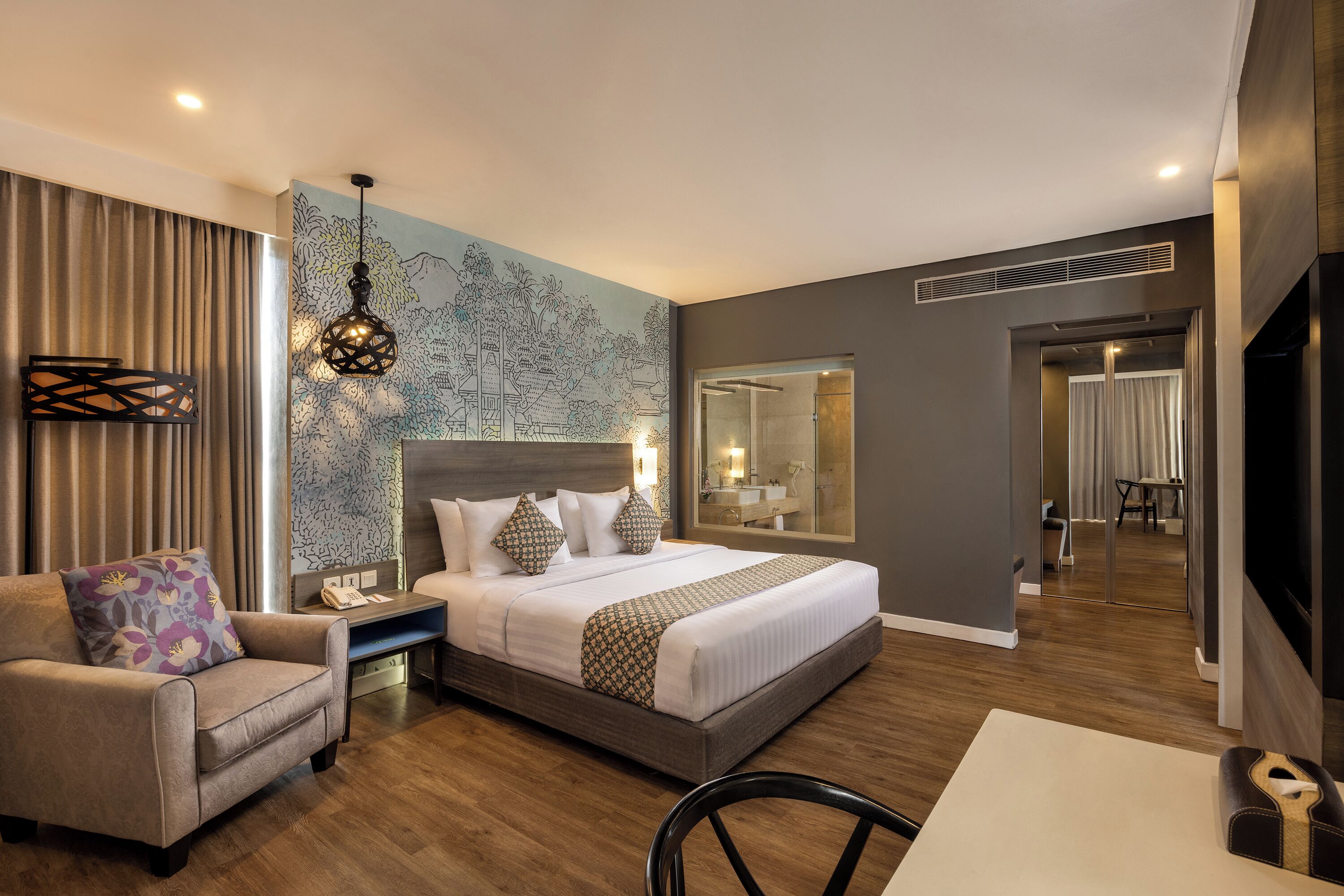Habitación de hotel moderna con una cama grande, un sofá, una mesa de comedor y un baño visible a través de una puerta abierta.