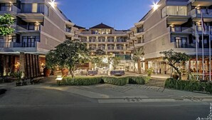 A multi-story hotel with a central courtyard, outdoor seating, and a well-lit facade. - Wyndham Garden Kuta Beach, Bali (Kuta)