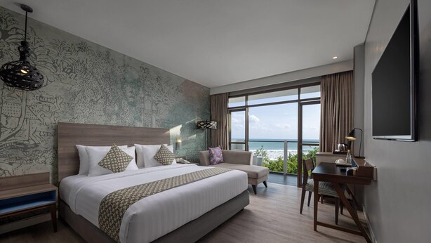 A modern hotel room with a large bed, a desk, and a view of the ocean. - Wyndham Garden Kuta Beach, Bali (Kuta)