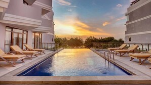 A swimming pool with lounge chairs and a sunset view. - Wyndham Garden Kuta Beach, Bali (Kuta)