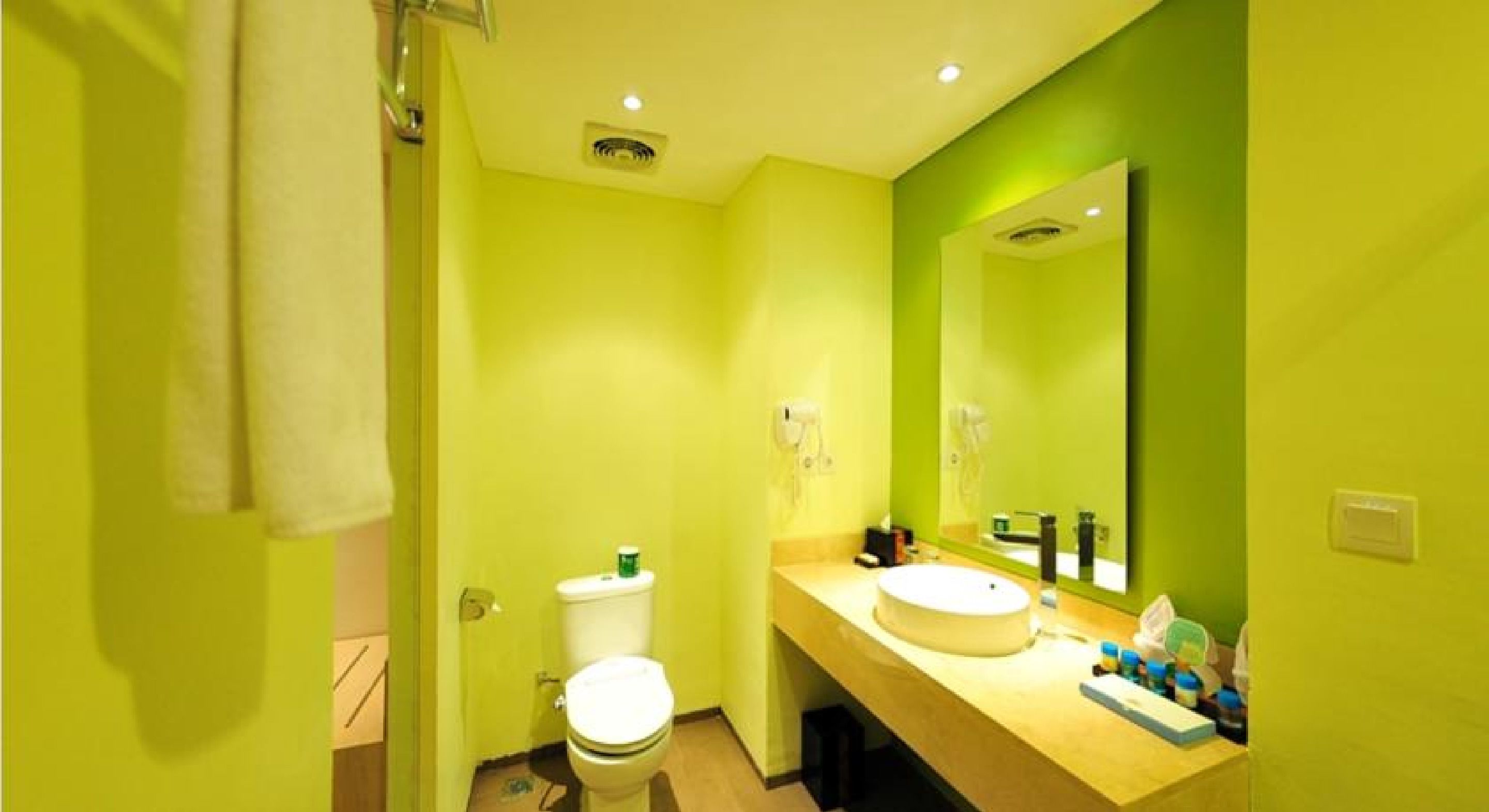 A bathroom with a toilet, sink, and mirror.