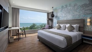 A modern hotel room with a large bed, a desk, and a view of the ocean. - Wyndham Garden Kuta Beach, Bali (Kuta)