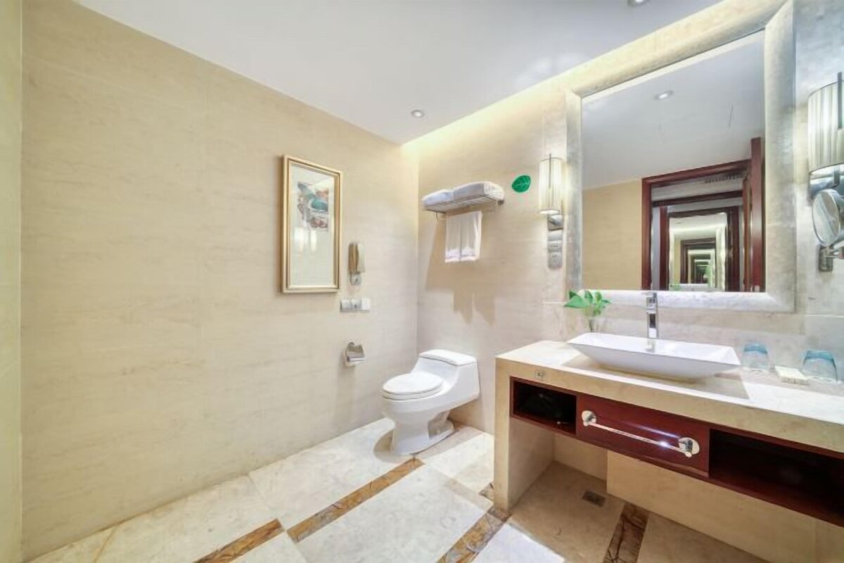 A modern bathroom with a white toilet, a large mirror, and a vessel sink.