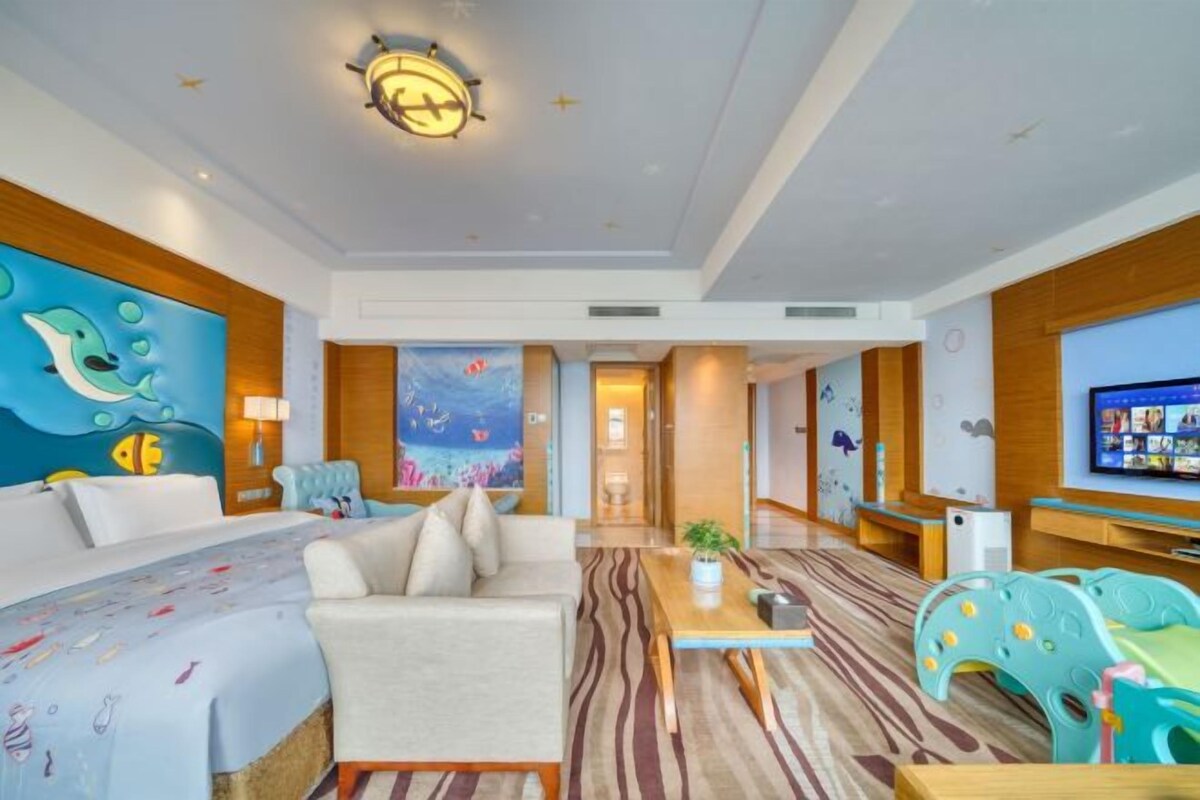 A hotel room with a bed, a sofa, a coffee table, and a TV.