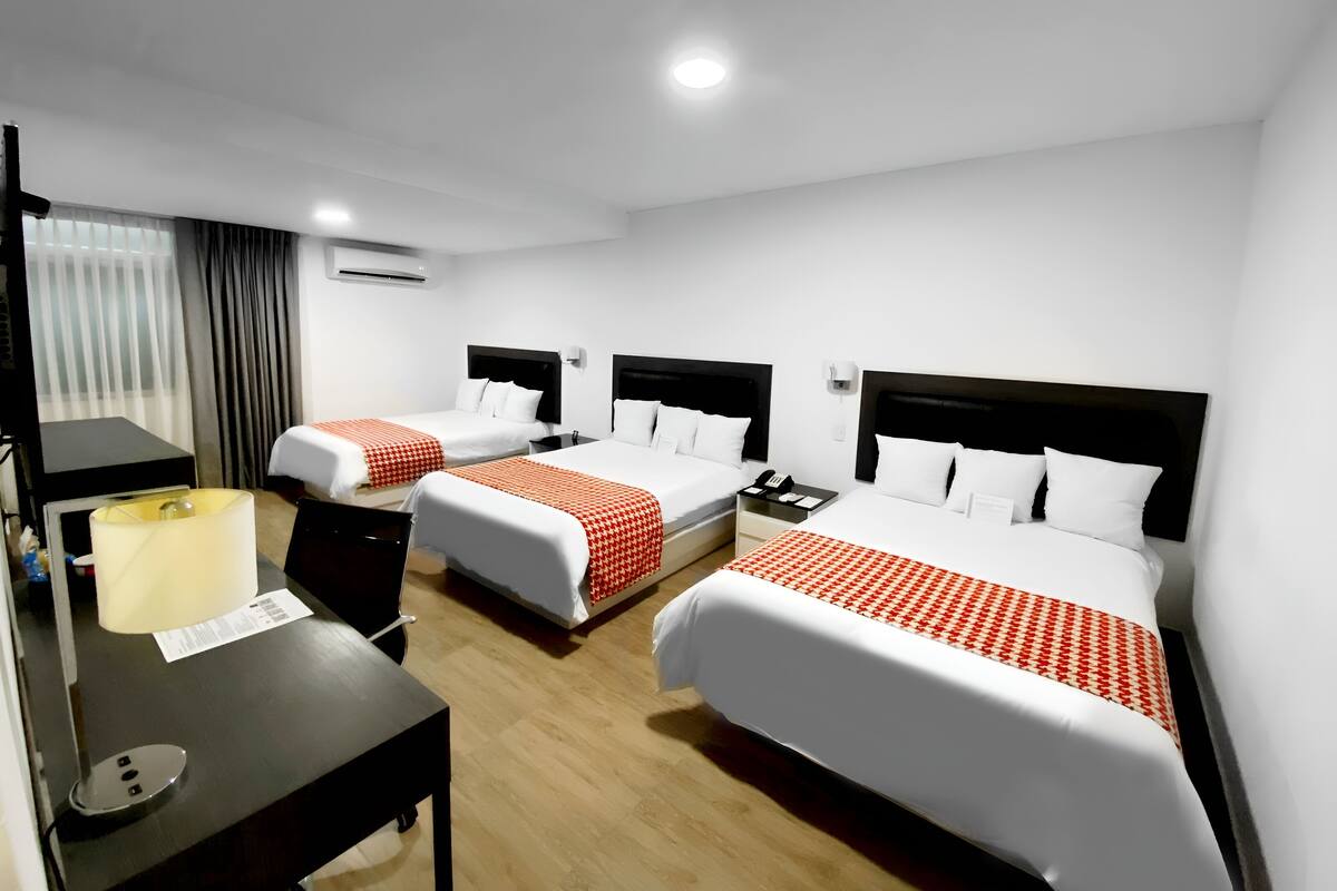 Habitación de hotel con dos camas, un escritorio, una lámpara y un teléfono.