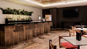 A bar area with a wooden ceiling, a wall-mounted TV, and a variety of bottles. - Wyndham Costa del Sol Tumbes (Tumbes)