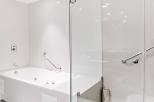 Un baño moderno con cabina de ducha de vidrio, una bañera blanca y un inodoro.