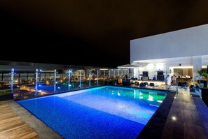 Una piscina al aire libre, sombrillas, sillones reclinables de piscina