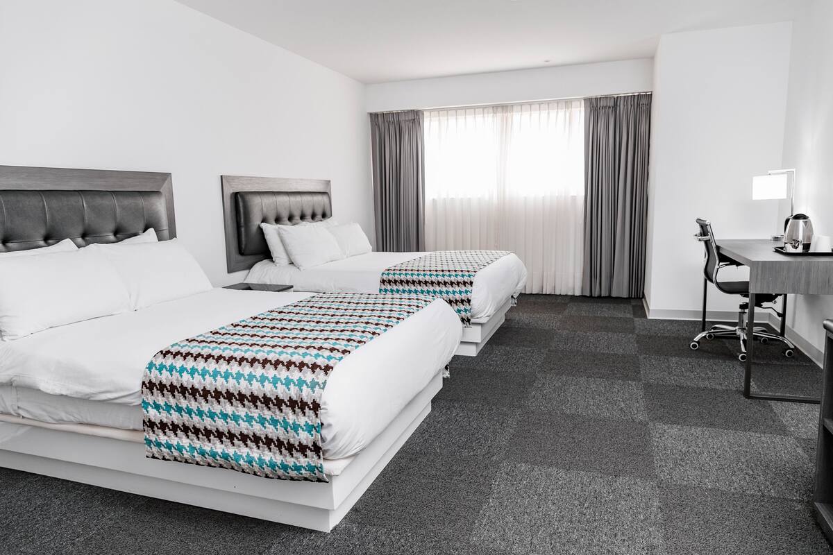 Habitación de hotel con dos camas, un escritorio y una silla.
