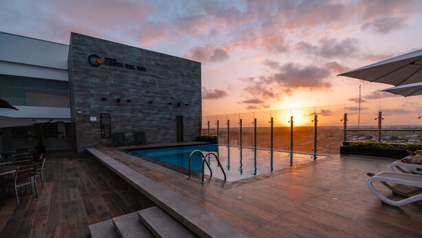 A rooftop pool area with a sunset view, a modern building with a logo, and outdoor seating. - Wyndham Costa del Sol Tumbes (Tumbes)