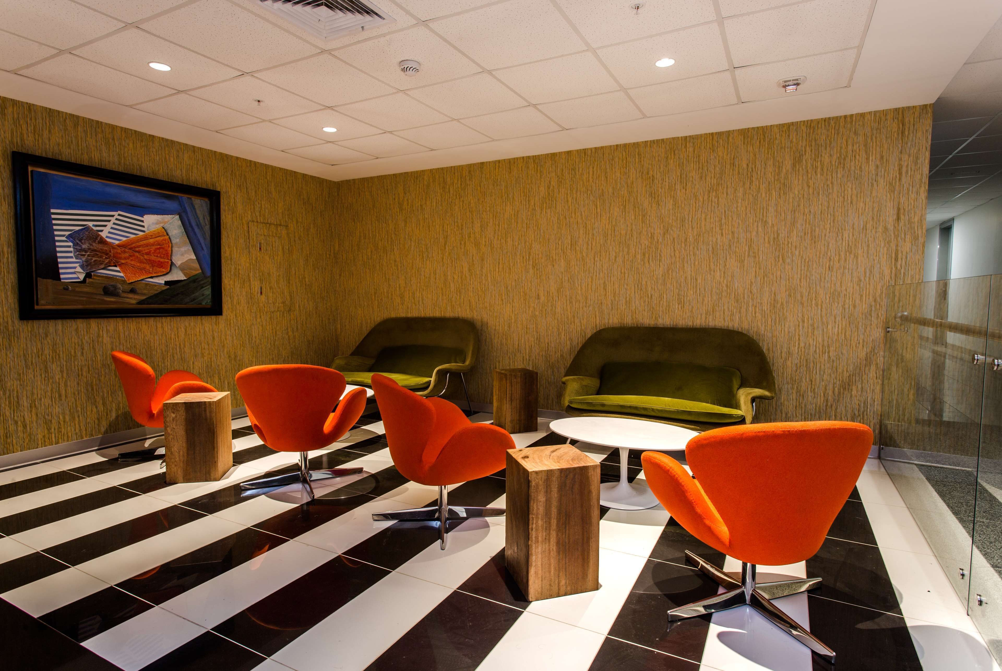 A modern conference room with a checkered floor, wooden tables, and orange chairs.