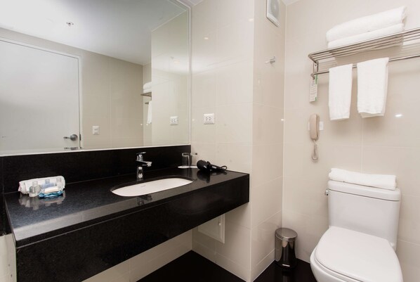 A modern bathroom with a black countertop sink, a mirror, a white toilet, and a towel rack.