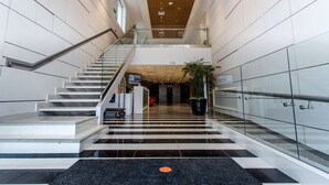A modern hotel lobby with a central staircase, a reception desk, and a large potted plant. - Wyndham Costa del Sol Tumbes (Tumbes)