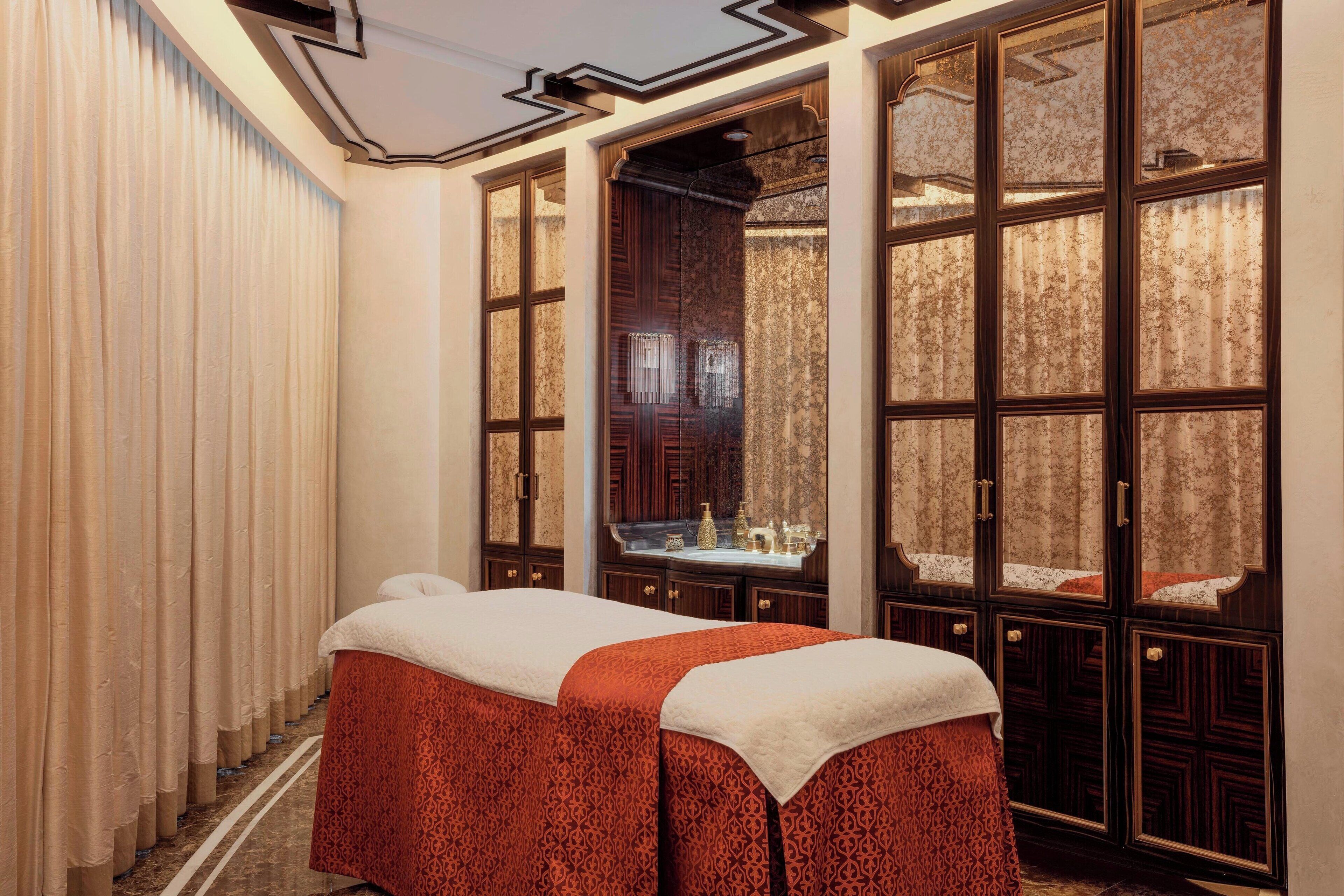 A spa room with a massage table, large windows, and a mirror.