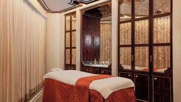 A spa room with a massage table, large windows, and a mirror.