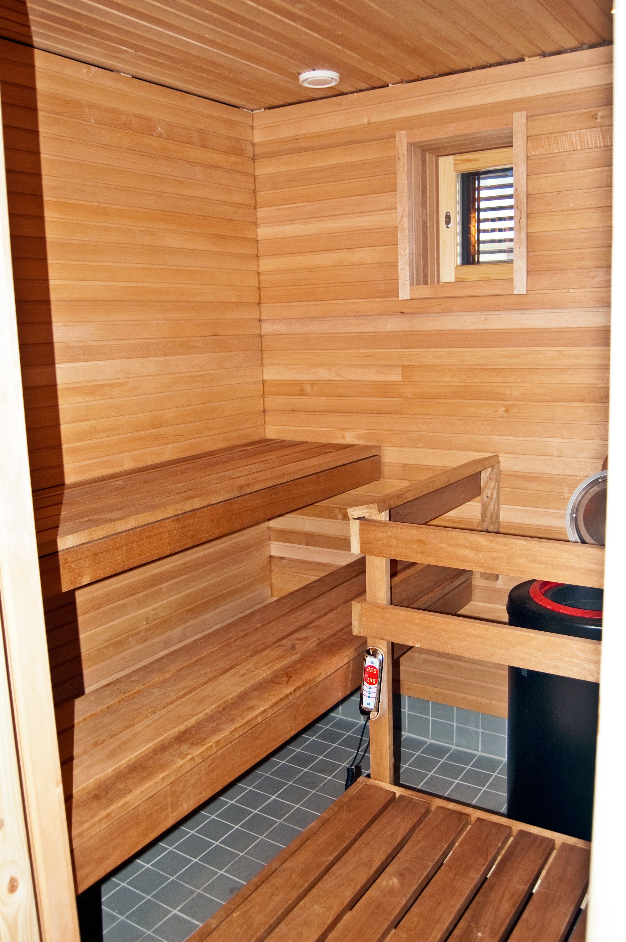 Een houten sauna met banken en een klein raam.