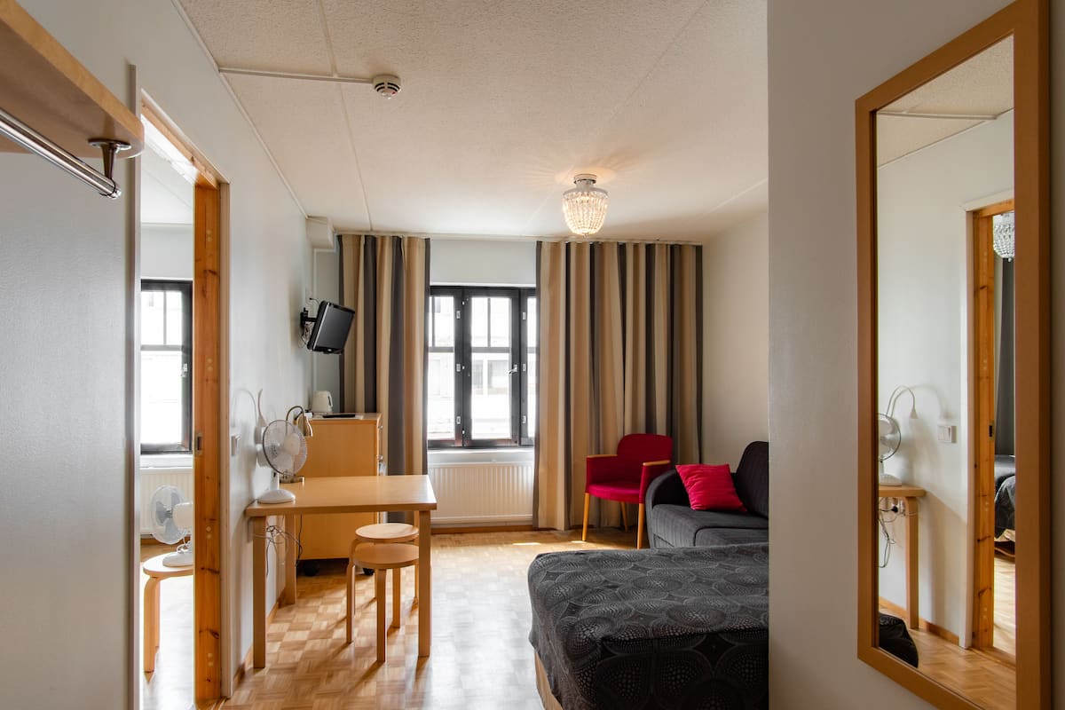 Ein Hotelzimmer mit Bett, Schreibtisch, Stuhl, Fernseher und einem fensterbepflanzten Fenster.