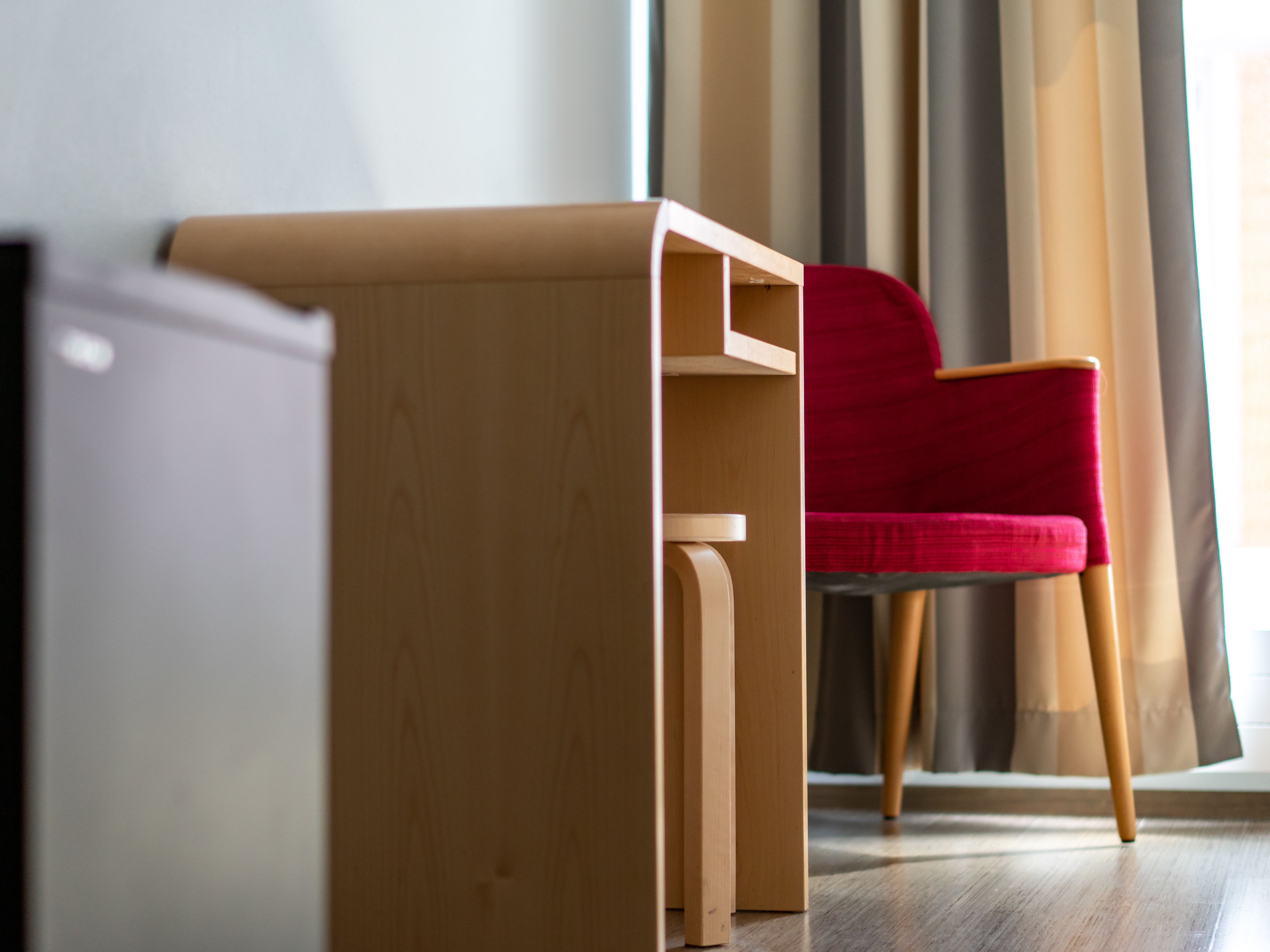 A compact room with a wooden desk and a red chair.