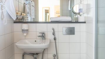 Pieni kylpyhuone, jossa on puinen katto, pesuallas, wc ja suihku.