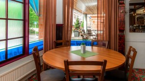 A dining area with a round table, wooden chairs, and a view of a street with a building and a Christmas tree. - Hotel Jahtihovi (Kuopio)