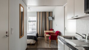 A compact hotel room with a kitchenette, a dining area, and a bed. - Hotel Jahtihovi (Kuopio)