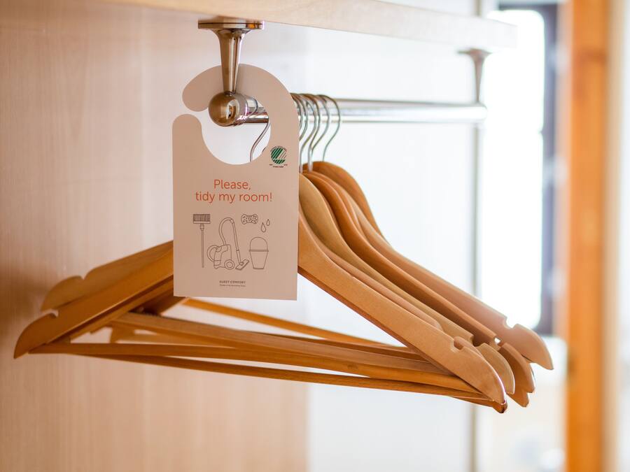 A wooden hanger rack with a tag requesting guests to tidy their room.