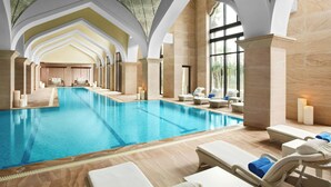 A large indoor swimming pool with lounge chairs and candles.