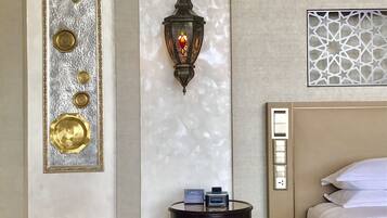 A hotel room with a bed, a wall-mounted decorative panel, a wall-mounted lantern, a small barrel with a lock, and a power outlet.
