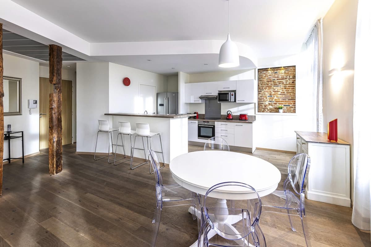 Een moderne keuken met witte kastjes, een roestvrijstalen koelkast en een magnetron.