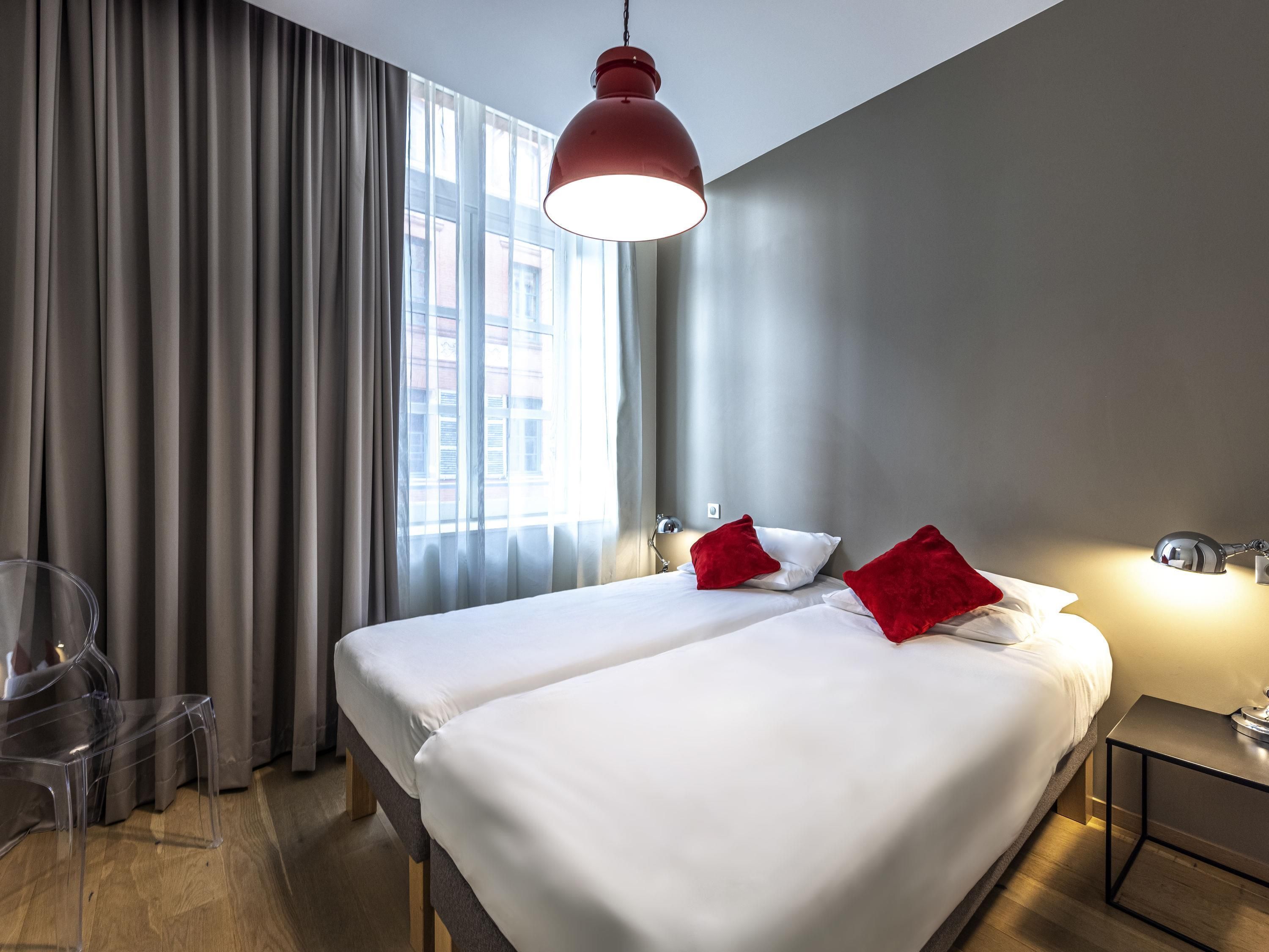 A hotel room with two beds, a desk, and a chair.